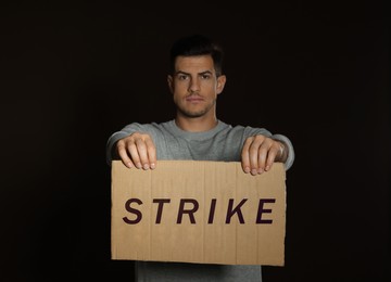 Man with Strike sign on dark background