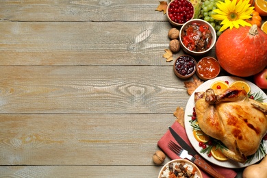 Photo of Traditional Thanksgiving day feast with delicious cooked turkey and other seasonal dishes served on wooden table, flat lay. Space for text