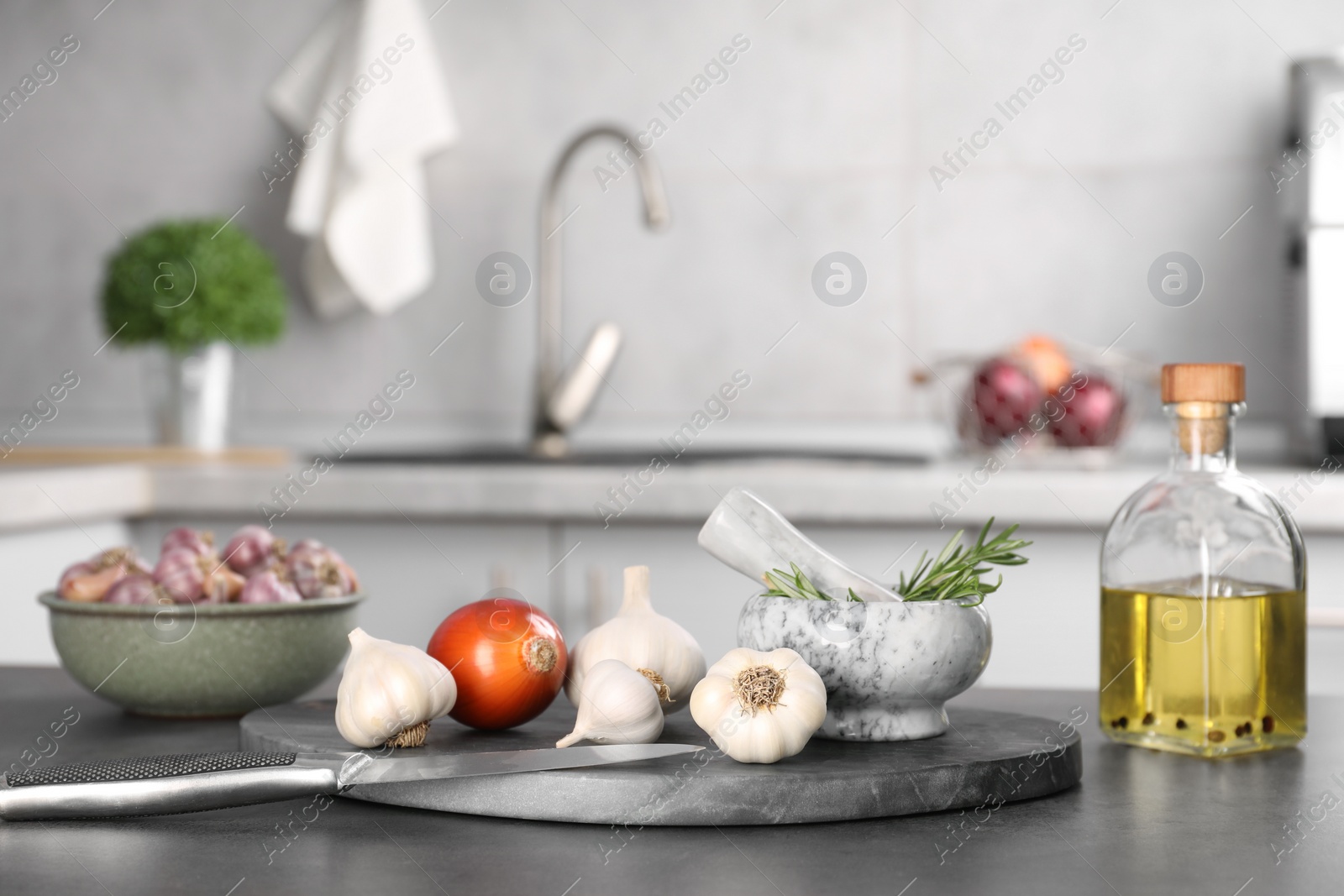 Photo of Fresh raw garlic, onion, rosemary and oil on grey table