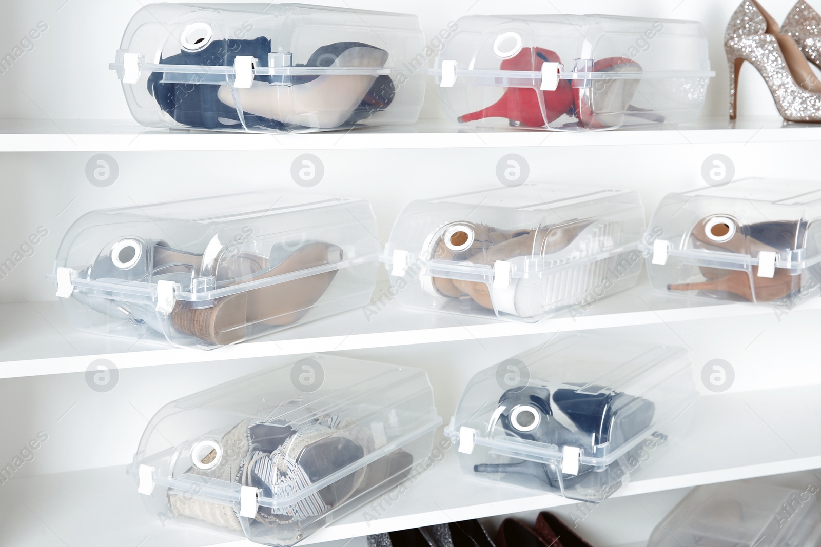 Photo of Footwear and plastic boxes on shelves in wardrobe. Shoe storage organization