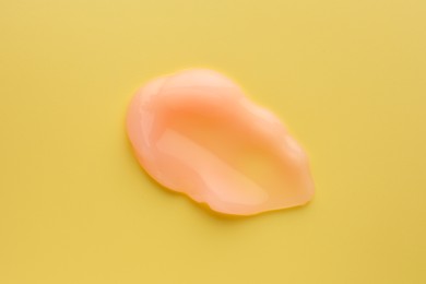 Photo of Sample of face cream on yellow background, top view