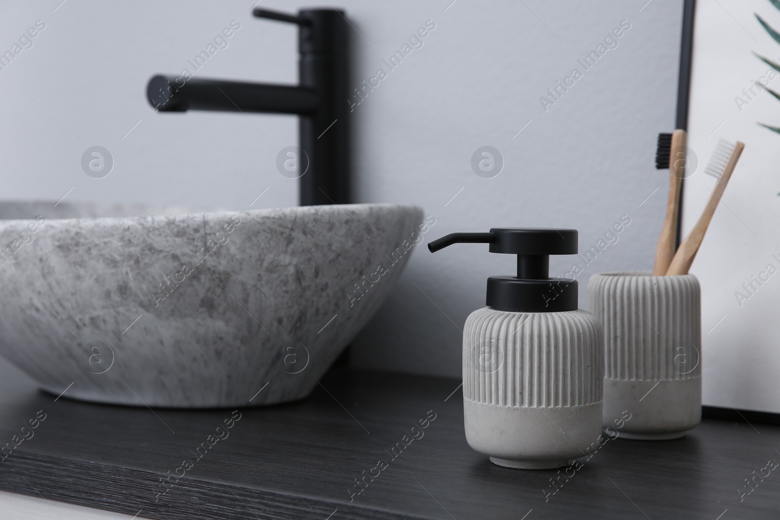 Photo of Dispenser of liquid soap and toothbrushes near sink in bathroom. Space for text