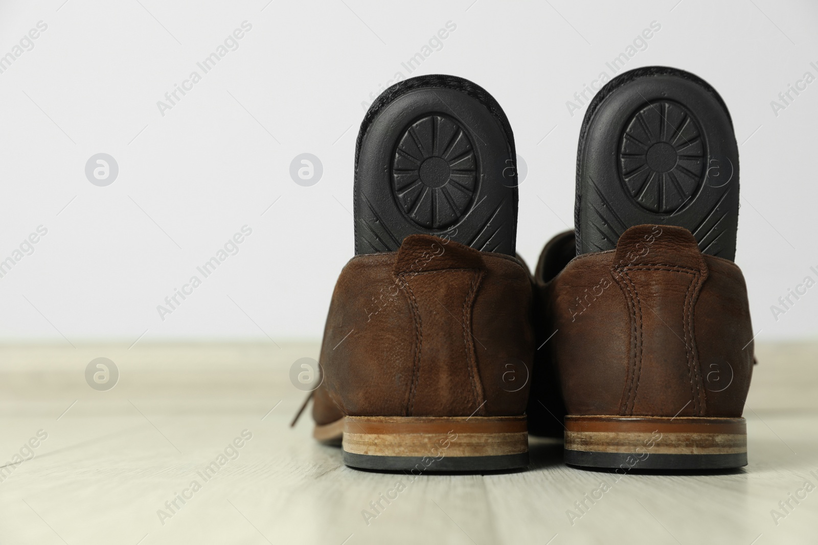 Photo of Orthopedic insoles in shoes on floor, closeup. Space for text