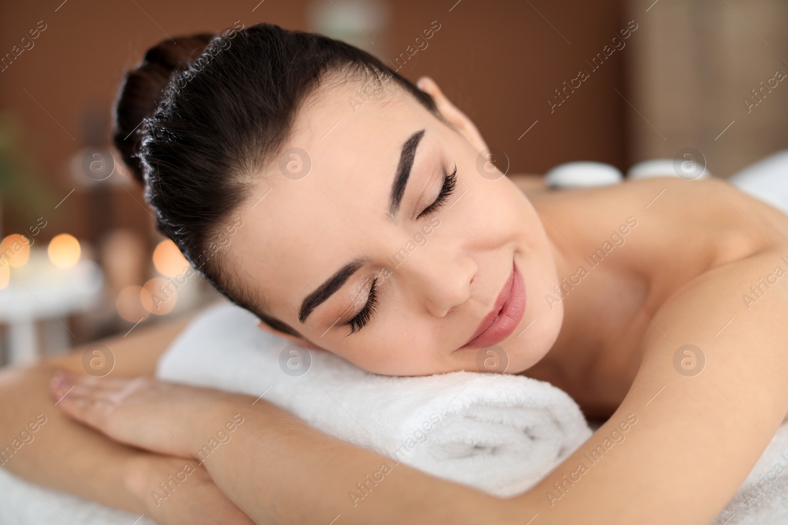 Photo of Young woman undergoing hot stone therapy in spa salon