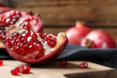 Photo of Ripe pomegranates on wooden board, closeup with space for text