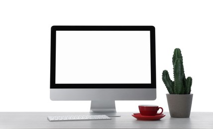 Photo of Computer, potted cactus and cup of drink on table against white background. Stylish workplace