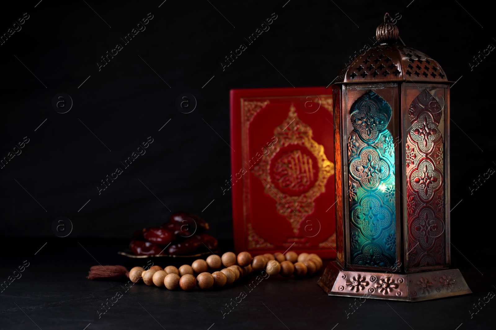 Photo of Composition with Arabic lantern and quran on black table. Space for text