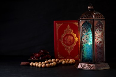 Photo of Composition with Arabic lantern and quran on black table. Space for text
