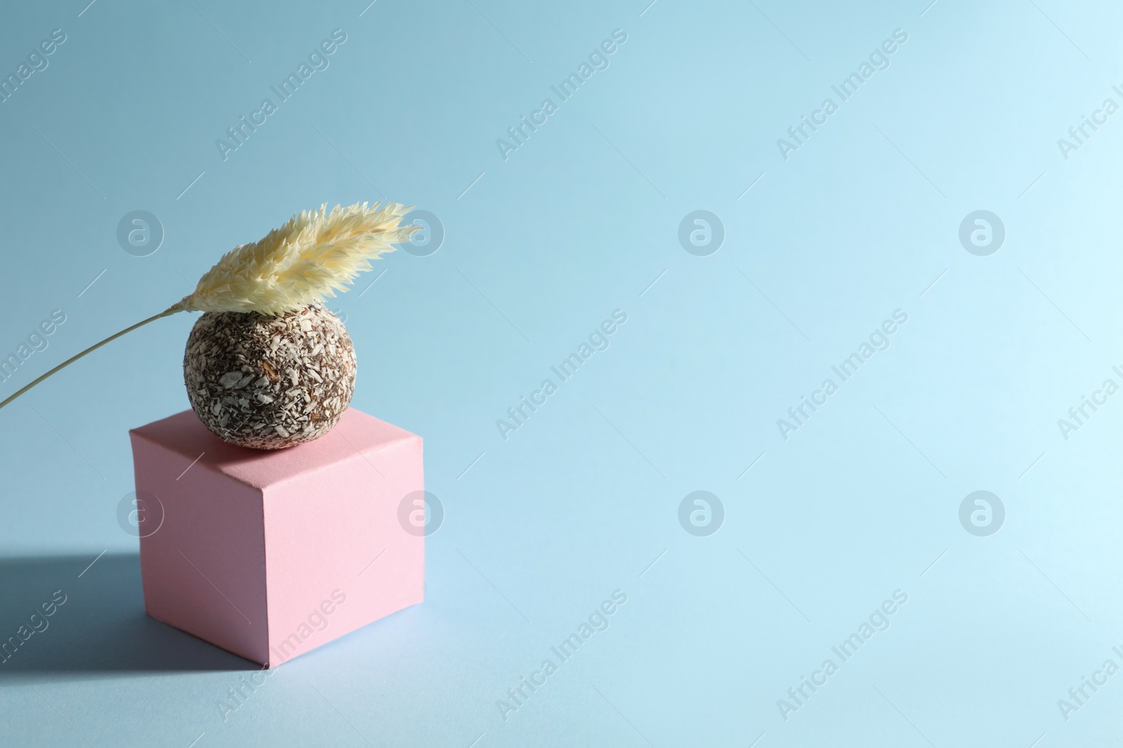 Photo of Minimalistic composition with delicious vegan candy ball on light blue background. Space for text