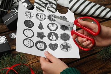 Woman making advent calendar at wooden table, closeup