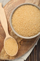 Photo of Brown sugar in bowl and spoon on table, flat lay