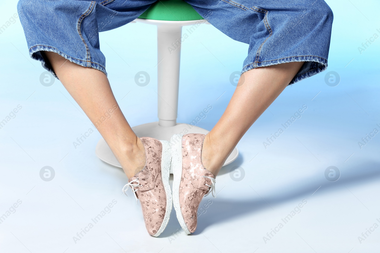 Photo of Woman in stylish shoes on stool against color background, closeup