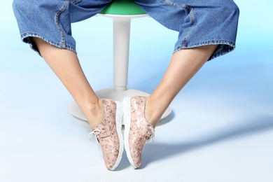 Photo of Woman in stylish shoes on stool against color background, closeup