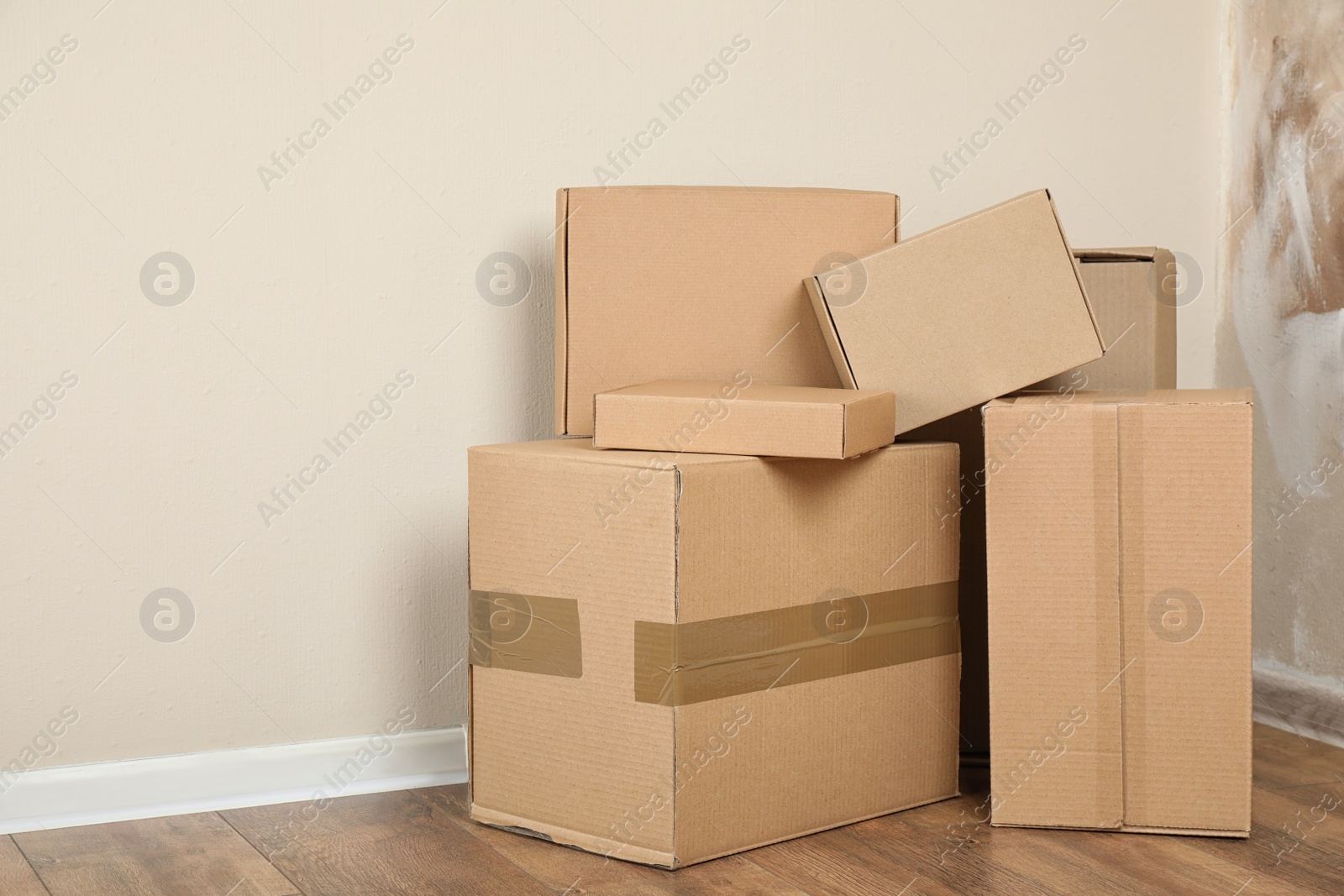 Photo of Pile of cardboard boxes near light wall indoors