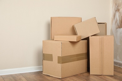 Photo of Pile of cardboard boxes near light wall indoors