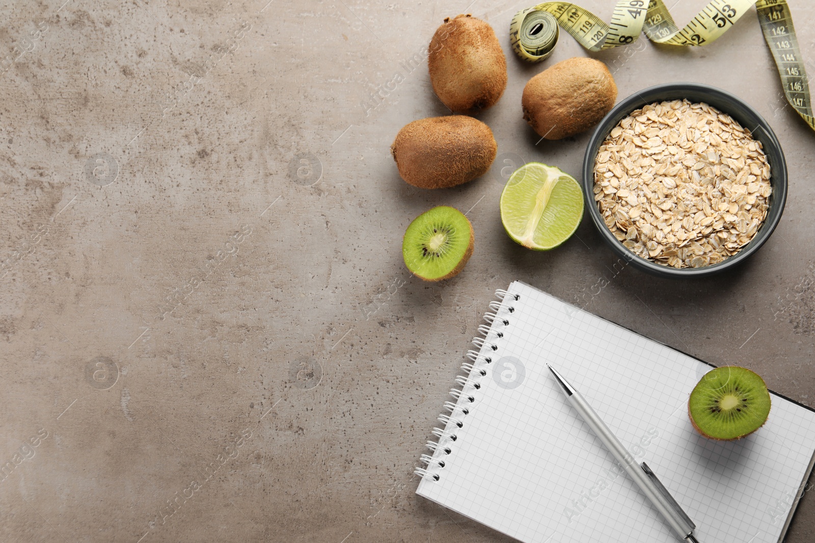 Photo of Healthy diet. Notebook, measuring tape, pen and products on grey table, flat lay. Space for text