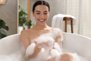 Beautiful young woman taking bubble bath at home