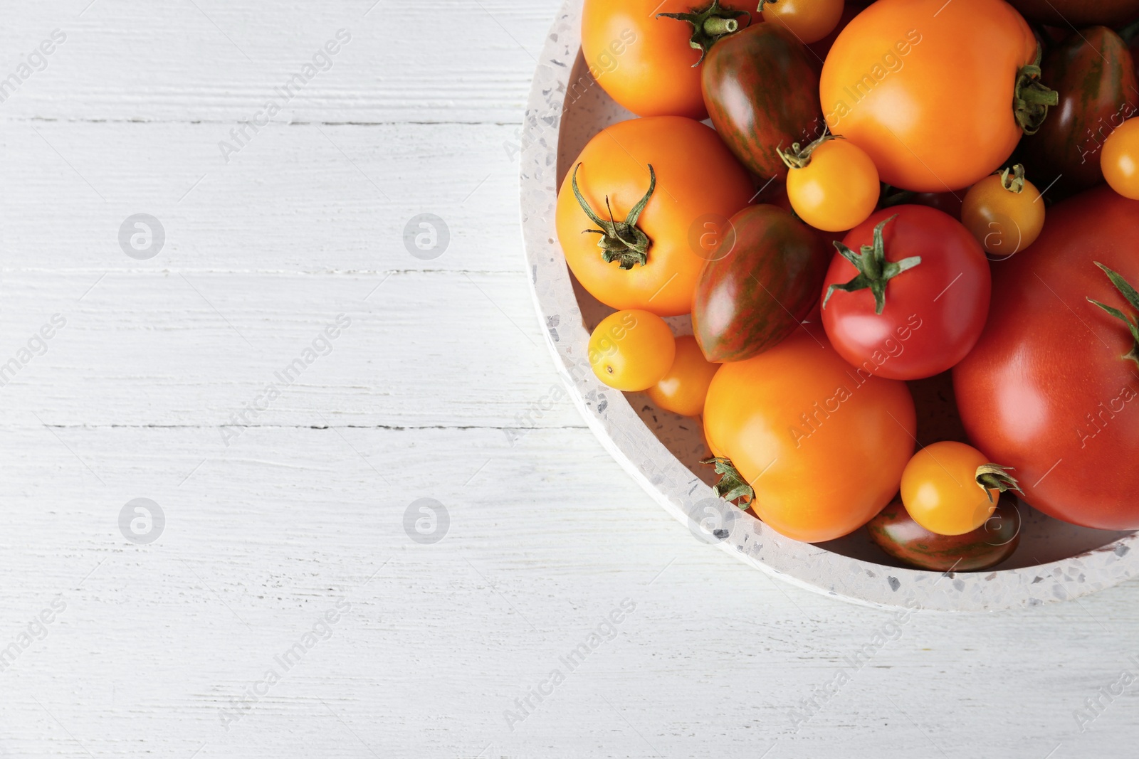 Photo of Fresh ripe tomatoes on white wooden table, top view. Space for text