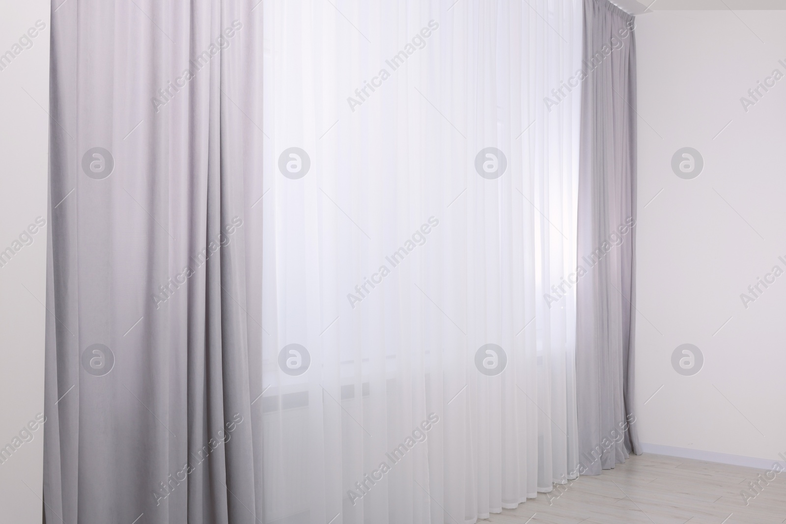 Photo of Light grey window curtains and white tulle indoors