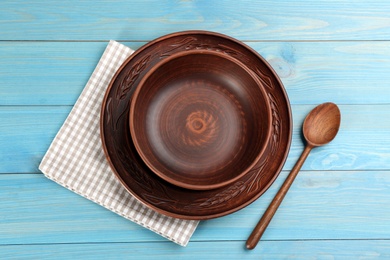 Photo of Set of clay utensils on light blue wooden table, flat lay