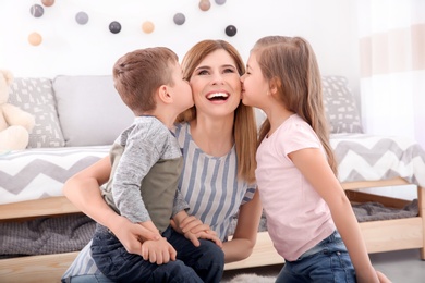 Photo of Cute little children kissing their nanny at home