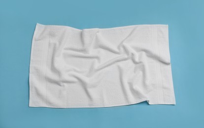 Photo of Crumpled white beach towel on light blue background, top view