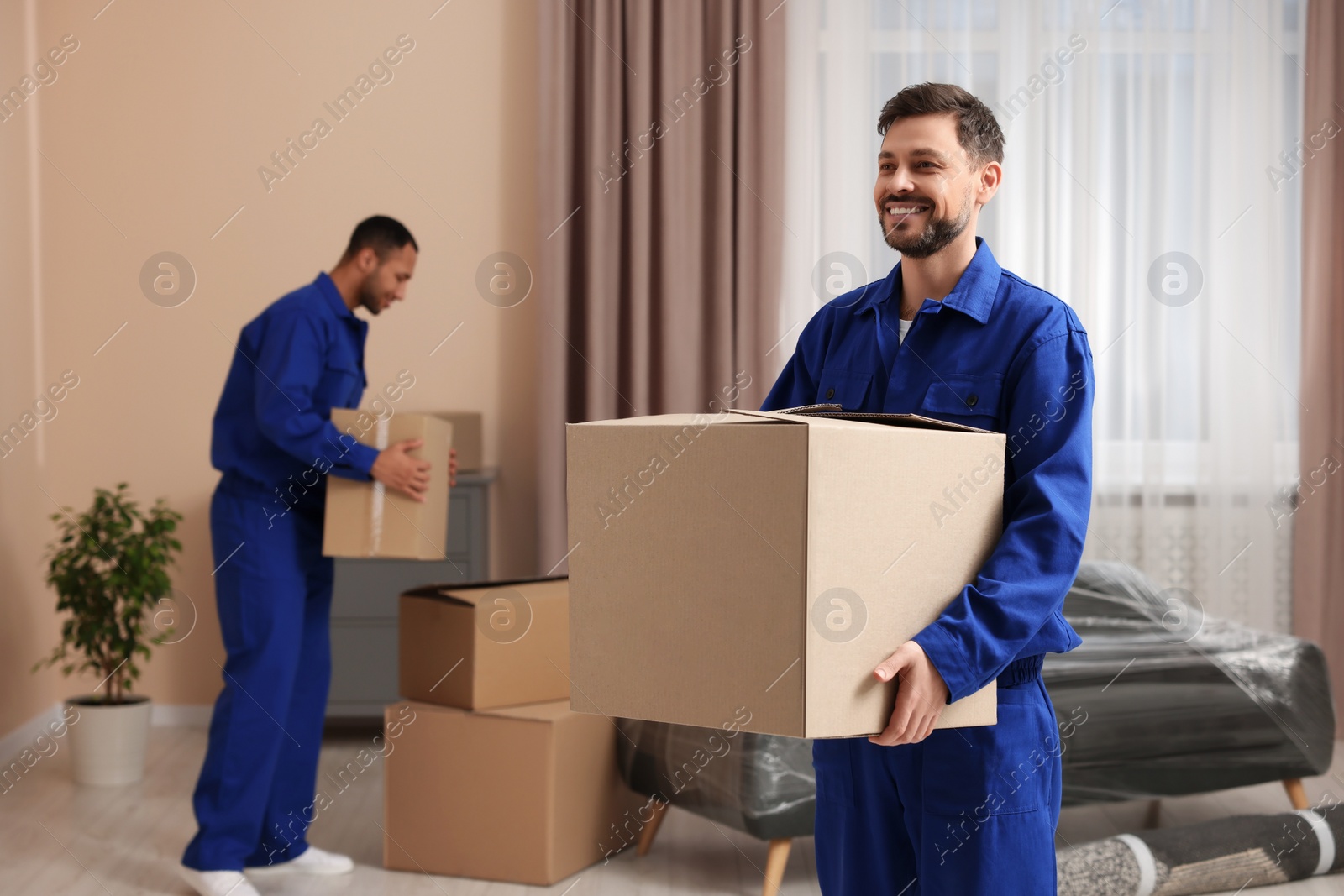 Photo of Male movers with cardboard boxes in new house