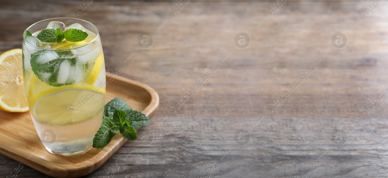 Image of Tasty refreshing soda drink with lemon slices and mint on wooden table. Banner design with space for text