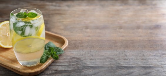 Image of Tasty refreshing soda drink with lemon slices and mint on wooden table. Banner design with space for text