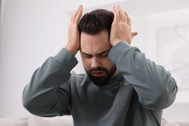 Young man suffering from headache at home