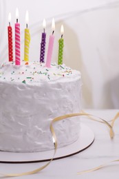 Delicious cake with cream and burning candles on white marble table, closeup