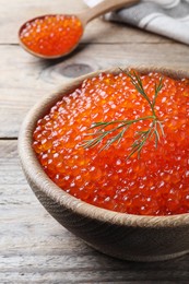 Photo of Bowl and spoon with delicious red caviar on wooden table