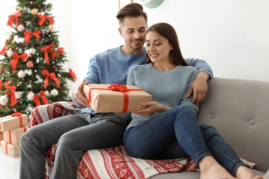 Photo of Young couple with Christmas gift at home