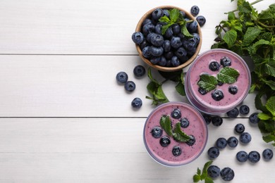 Photo of Glasses of blueberry smoothie with mint and fresh berries on white wooden table, flat lay. Space for text