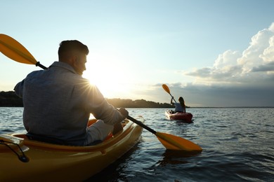 Couple kayaking on river at sunset, back view. Summer activity
