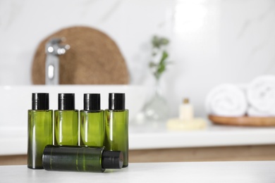 Mini bottles with cosmetic products on white table in bathroom. Space for text