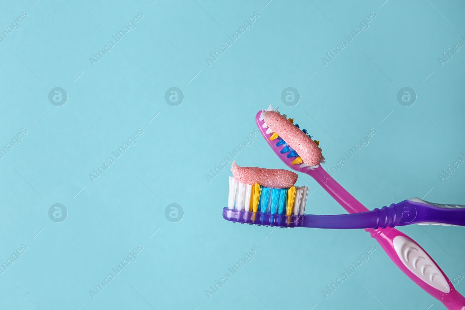 Photo of Toothbrushes with paste on color background, closeup