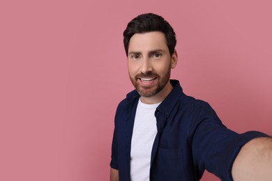 Photo of Smiling man taking selfie on pink background, space for text