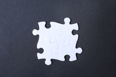 Photo of Blank white puzzle pieces on black background, flat lay