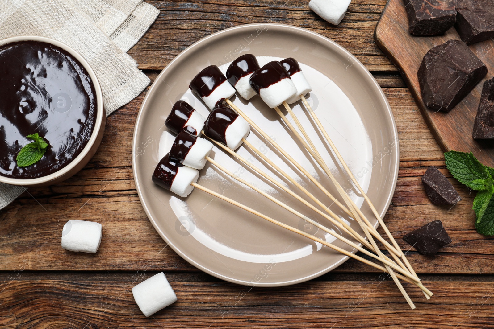 Photo of Delicious marshmallows covered with chocolate on wooden table, flat lay