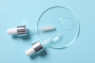 Photo of Sample of cosmetic serum and pipettes on light blue background, flat lay