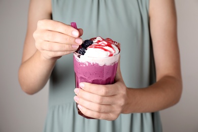 Woman with tasty milk shake on grey background, closeup