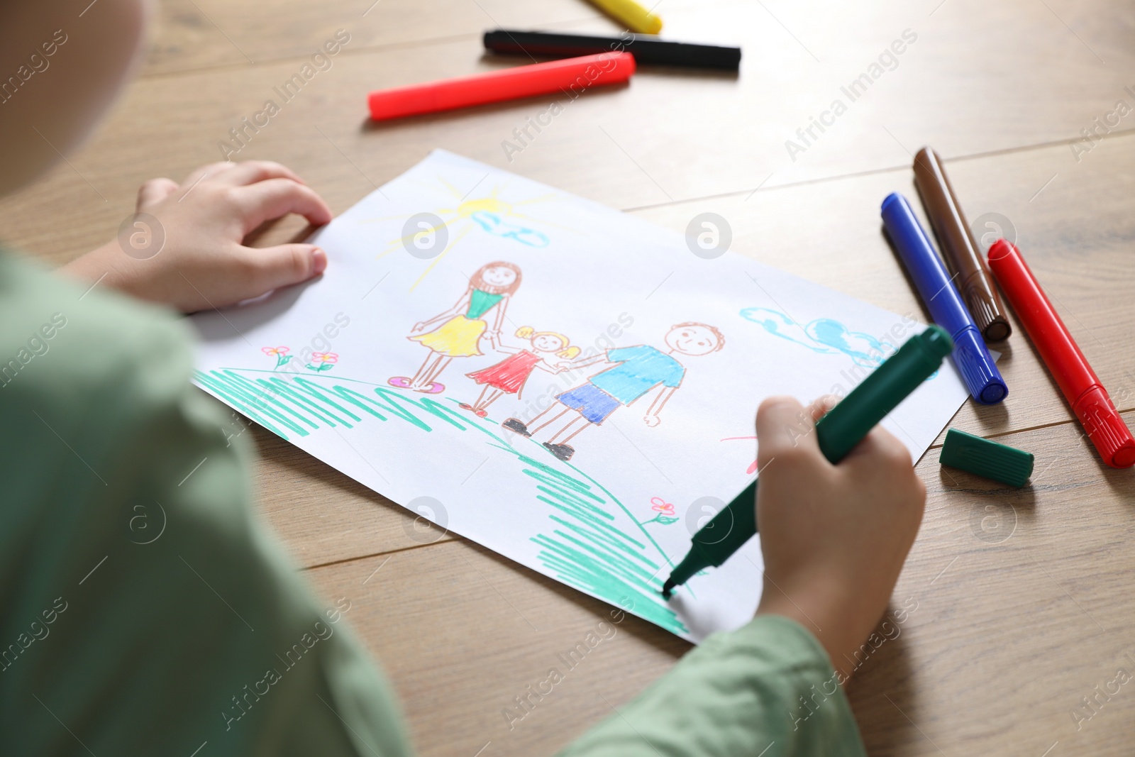 Photo of Little boy drawing picture with marker at wooden table, closeup. Child`s art