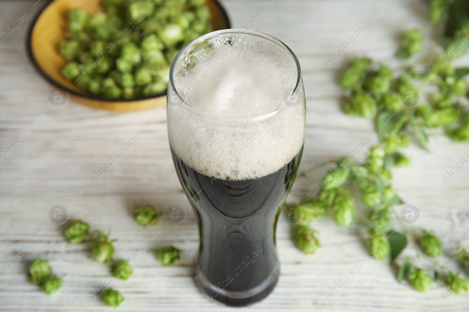 Photo of Composition with tasty beer and fresh green hops on wooden table
