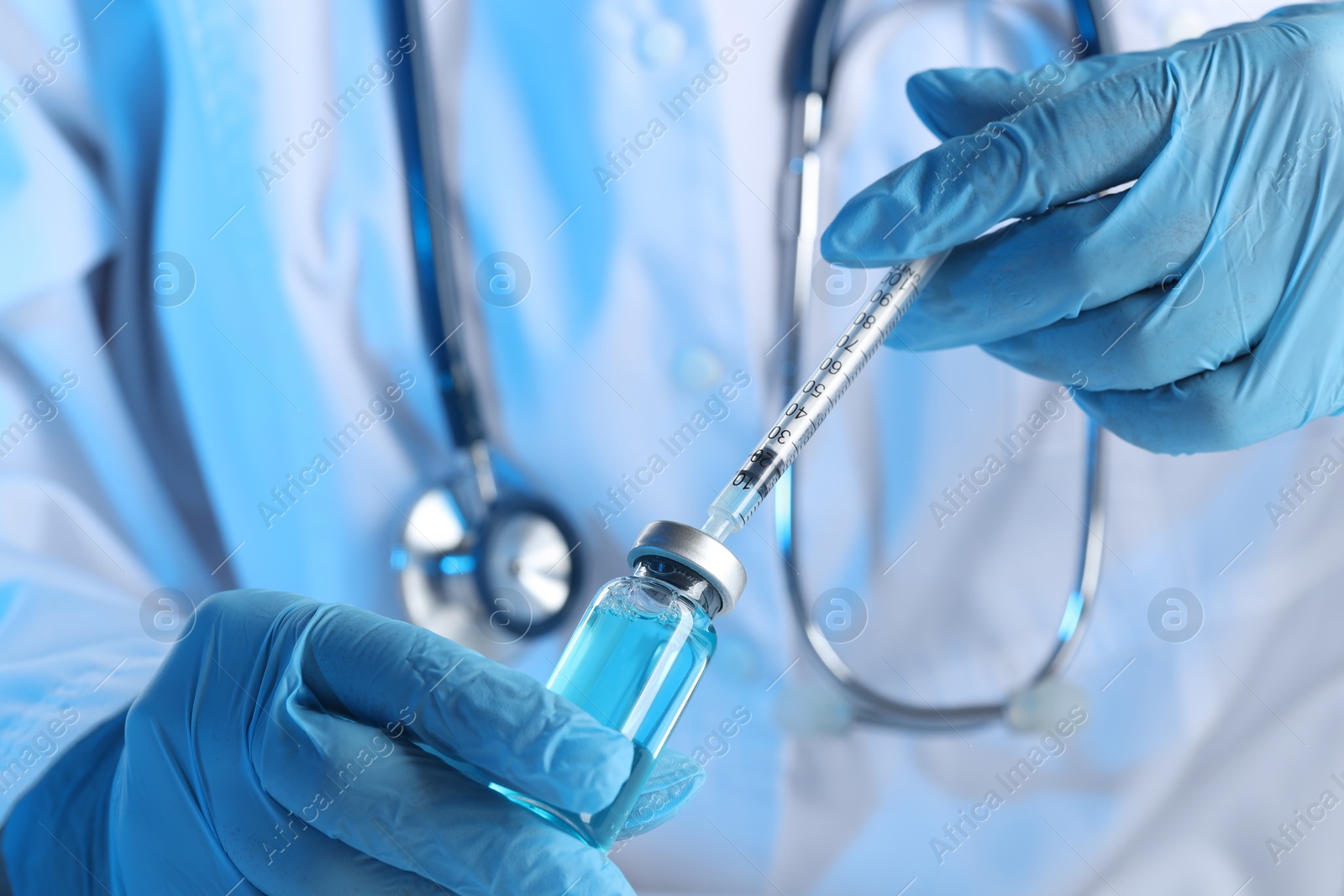 Photo of Doctor filling syringe with medication from glass vial, closeup