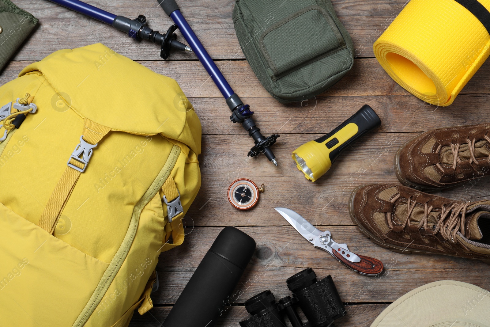 Photo of Flat lay composition with backpack and other different camping equipment for tourism on wooden background
