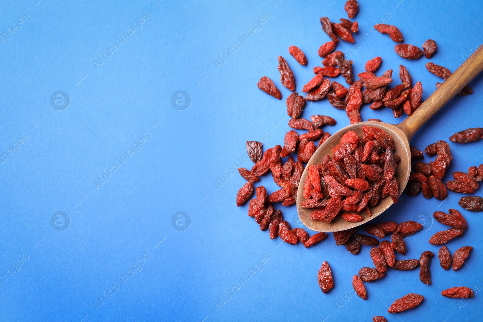 Photo of Dried goji berries on blue background, flat lay. Space for text