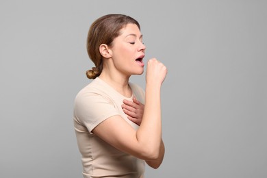 Photo of Woman coughing on light grey background. Sore throat