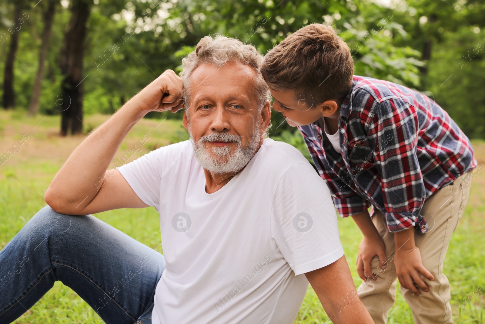 Photo of Cute little boy and grandfather spending time together in park