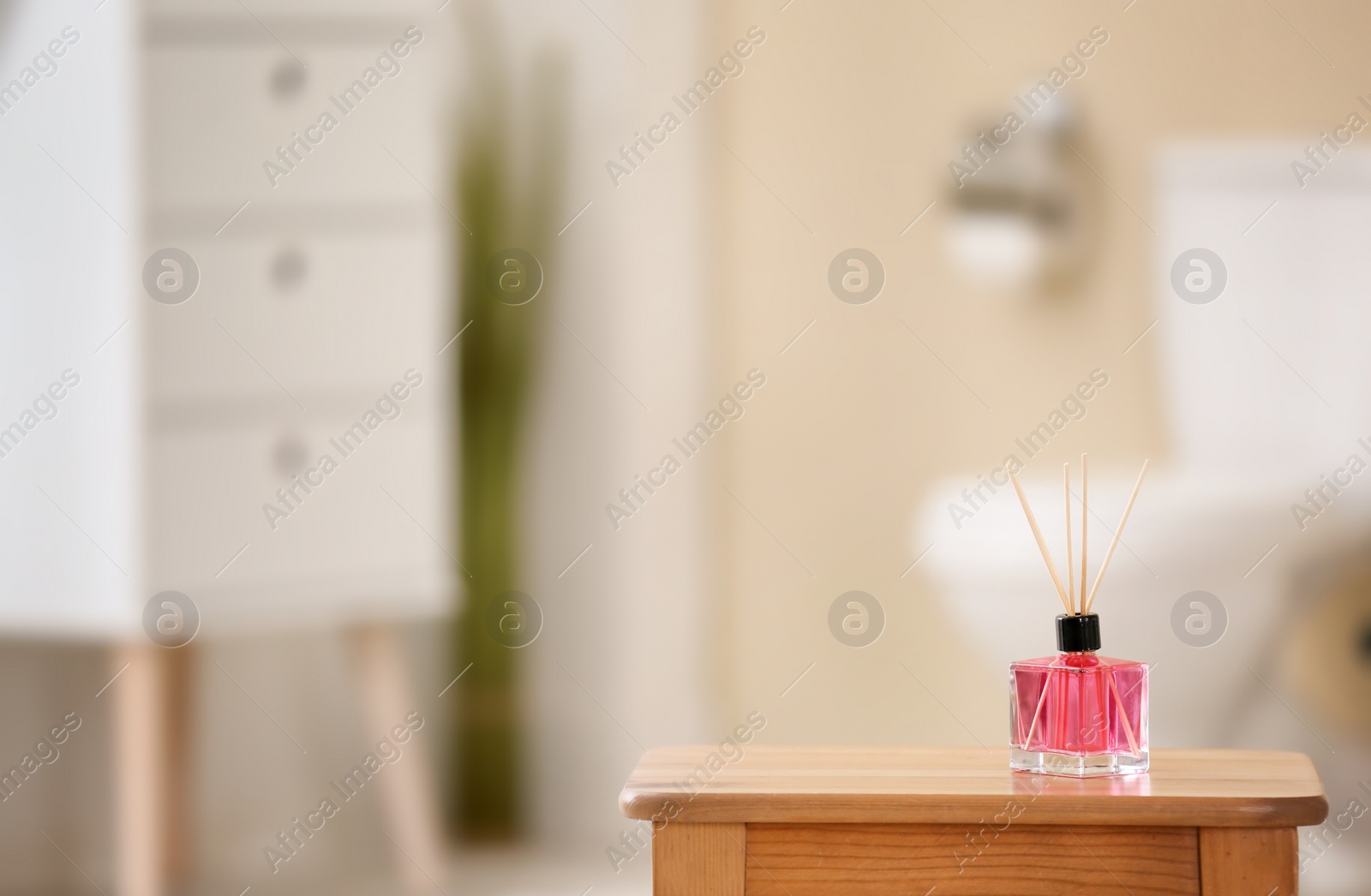 Photo of Aromatic reed air freshener on table against blurred background